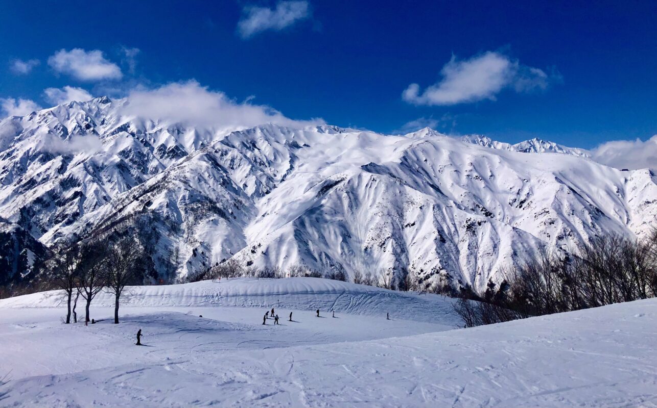 Wide angle view of Happo One Ski resort with moountain range in background and distant skiers in the foreground.