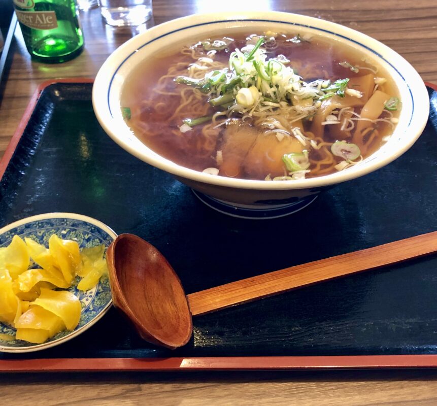 Image of a bowl of ramen on a tray with pickled vegetables at a restaurant next to Hakuba train station.