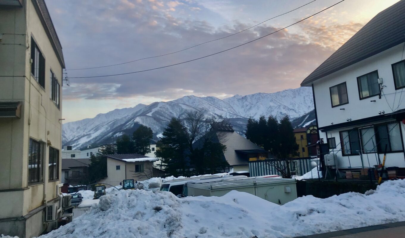 View of mountain range between local buildings, in the town of Hakuba.