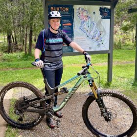 Rider in front of the Buxton mountain bike trails map, at the trailhead carpark.