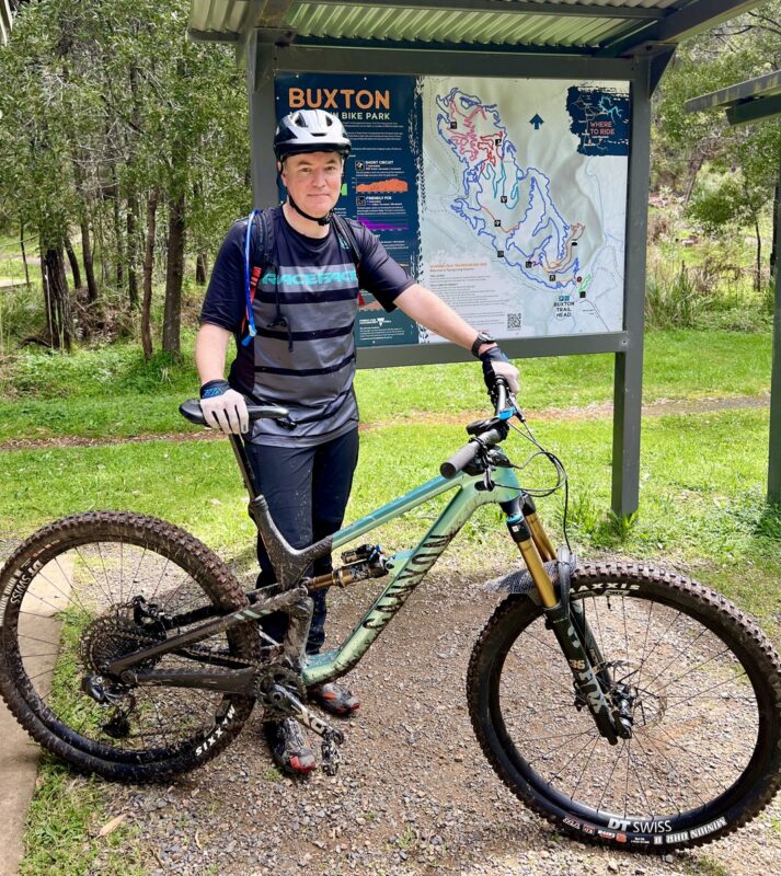 Rider in front of the Buxton mountain bike trails map, at the trailhead carpark.