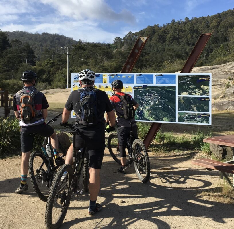 Mountain bike riders in front of trailhead map at Derby, Tasmania